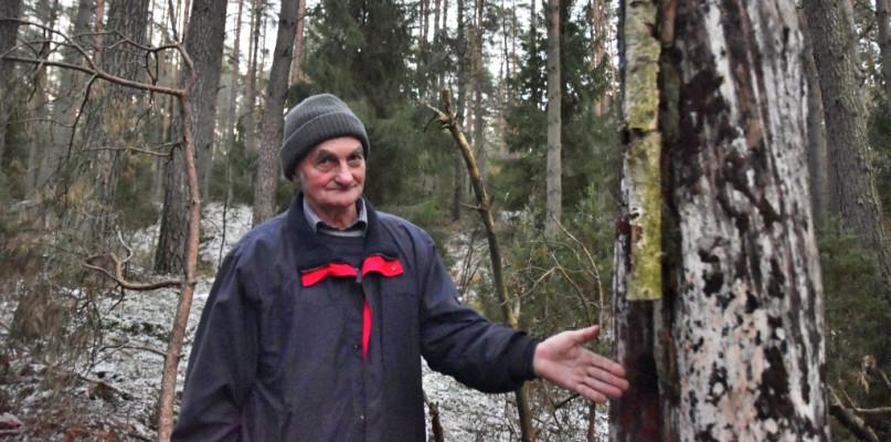 Jan Maniowski wskazuje miejsce, w którym jego brat napisał ołówkiem kopiowym datę śmierci Jana Ciemińskiego i nieznanego mężczyzny.