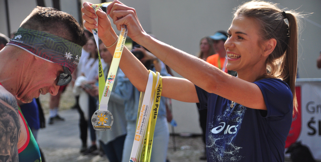 Mistrzyni Polski w półmaratonie wręcza medal kończącemu bieg zawodnikowi.